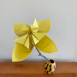 yellow kusudama origami flower in small striped vase