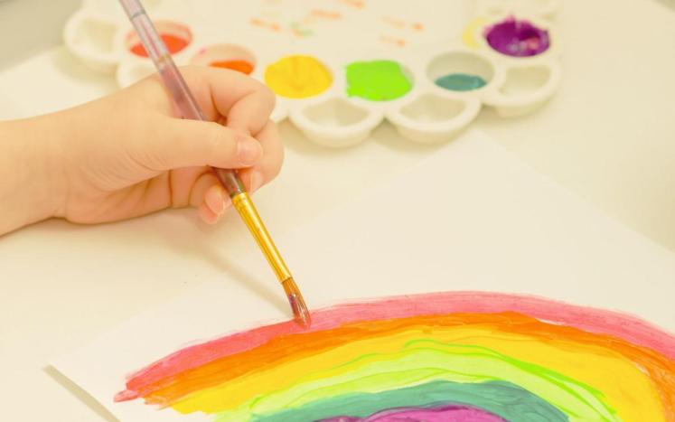 child's hand painting a rainbow